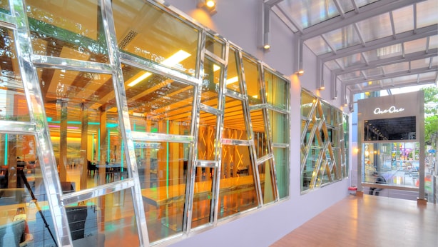 A modern interior with large glass windows, wooden flooring, and a visible store named "One One". - One One Bangkok Hotel (Bangkok)