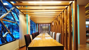 A conference room with a long table, chairs, and a view through large windows. - One One Bangkok Hotel (Bangkok)