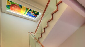 A wooden staircase with glass railings and a colorful stained glass window above. - One One Bangkok Hotel (Bangkok)
