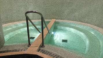 Un jacuzzi con una escalera metálica y un desagüe.