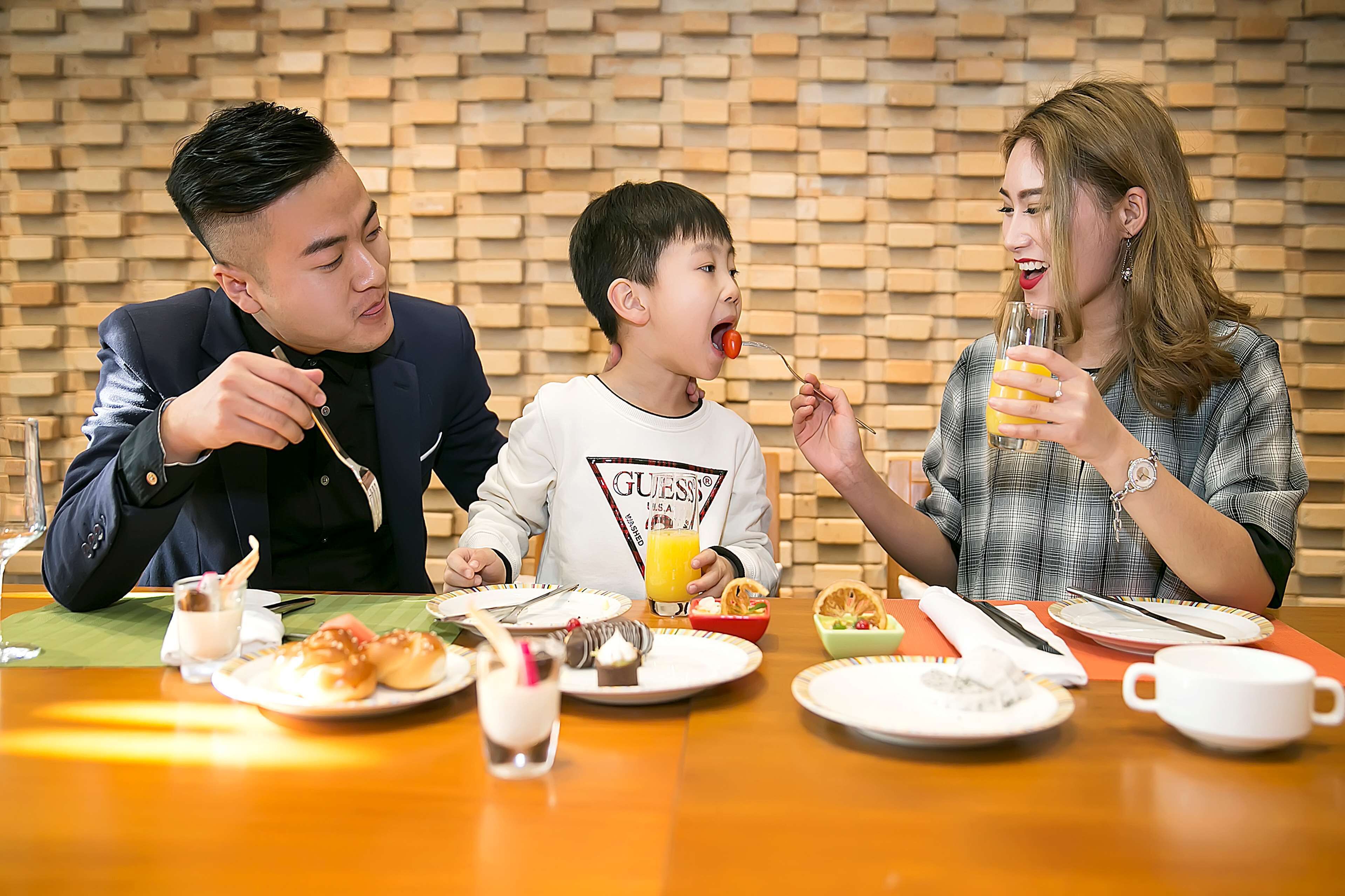 Three people dining at a table with various dishes and drinks.