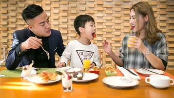 Three people dining at a table with various dishes and drinks.