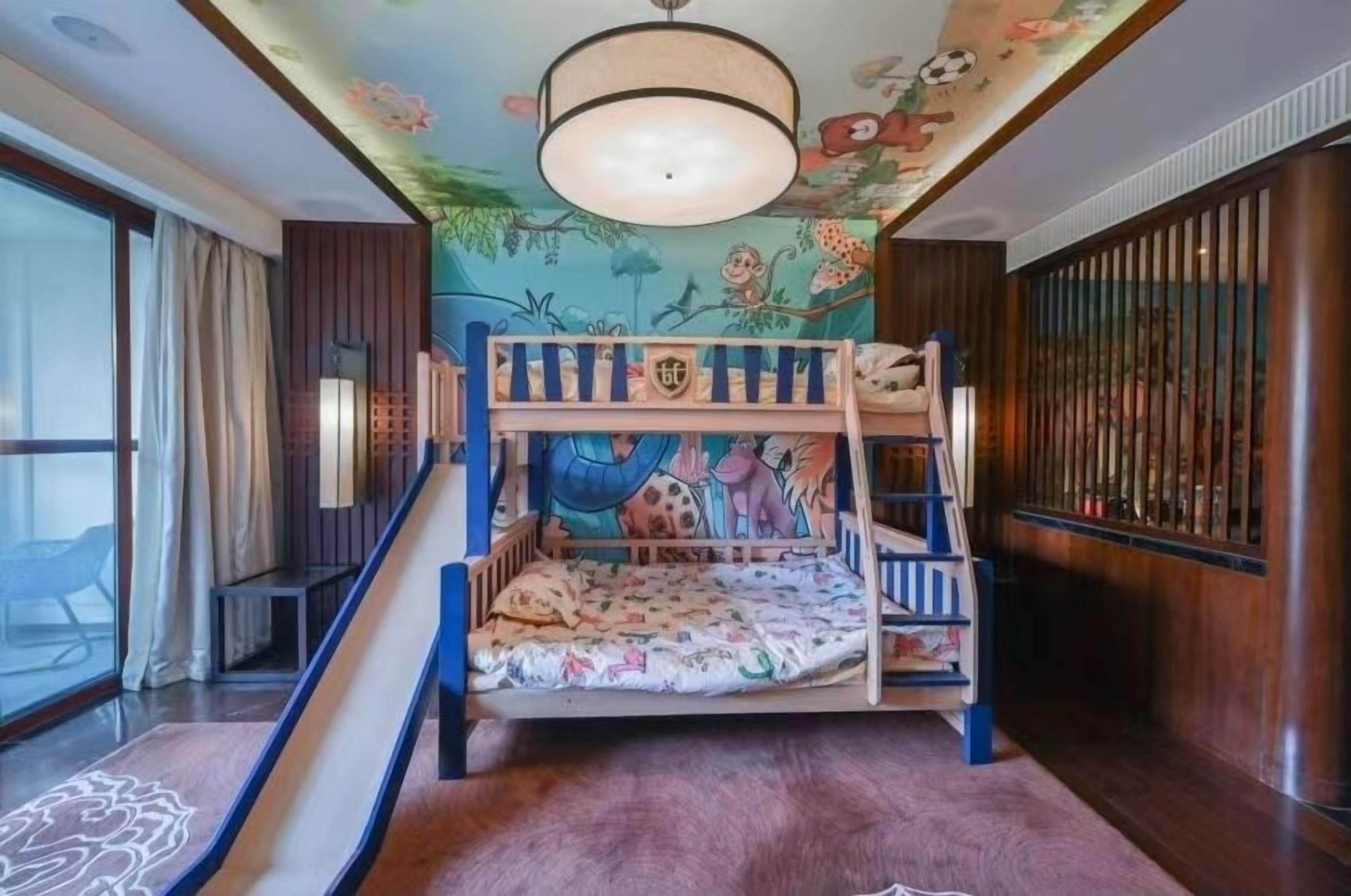 Una cama litera con tobogán, un mural en el techo y vistas al exterior.