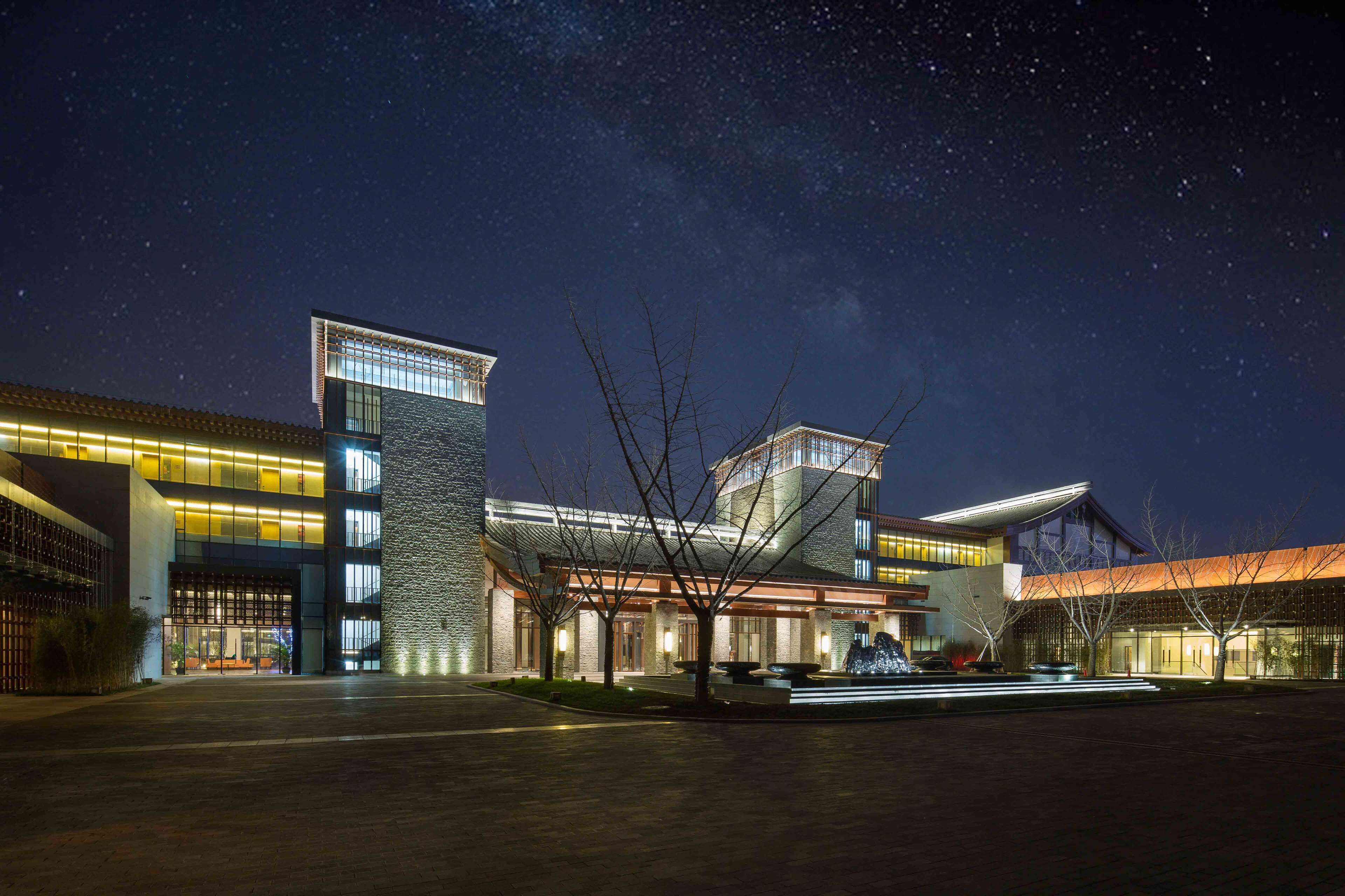 A modern hotel with a spacious entrance, multiple floors, and a well-lit facade.