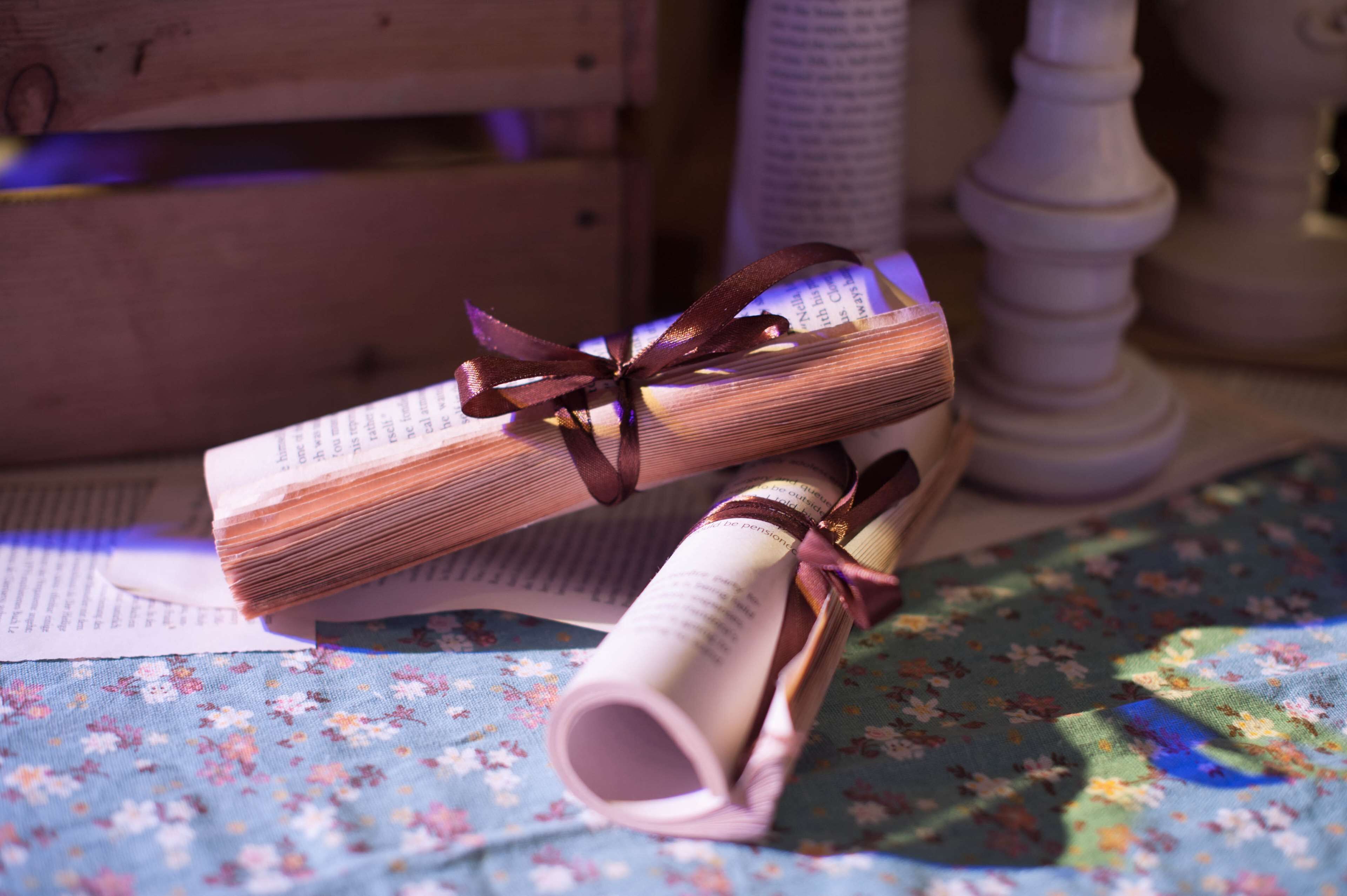 Two rolled-up documents tied with ribbons on a floral tablecloth.