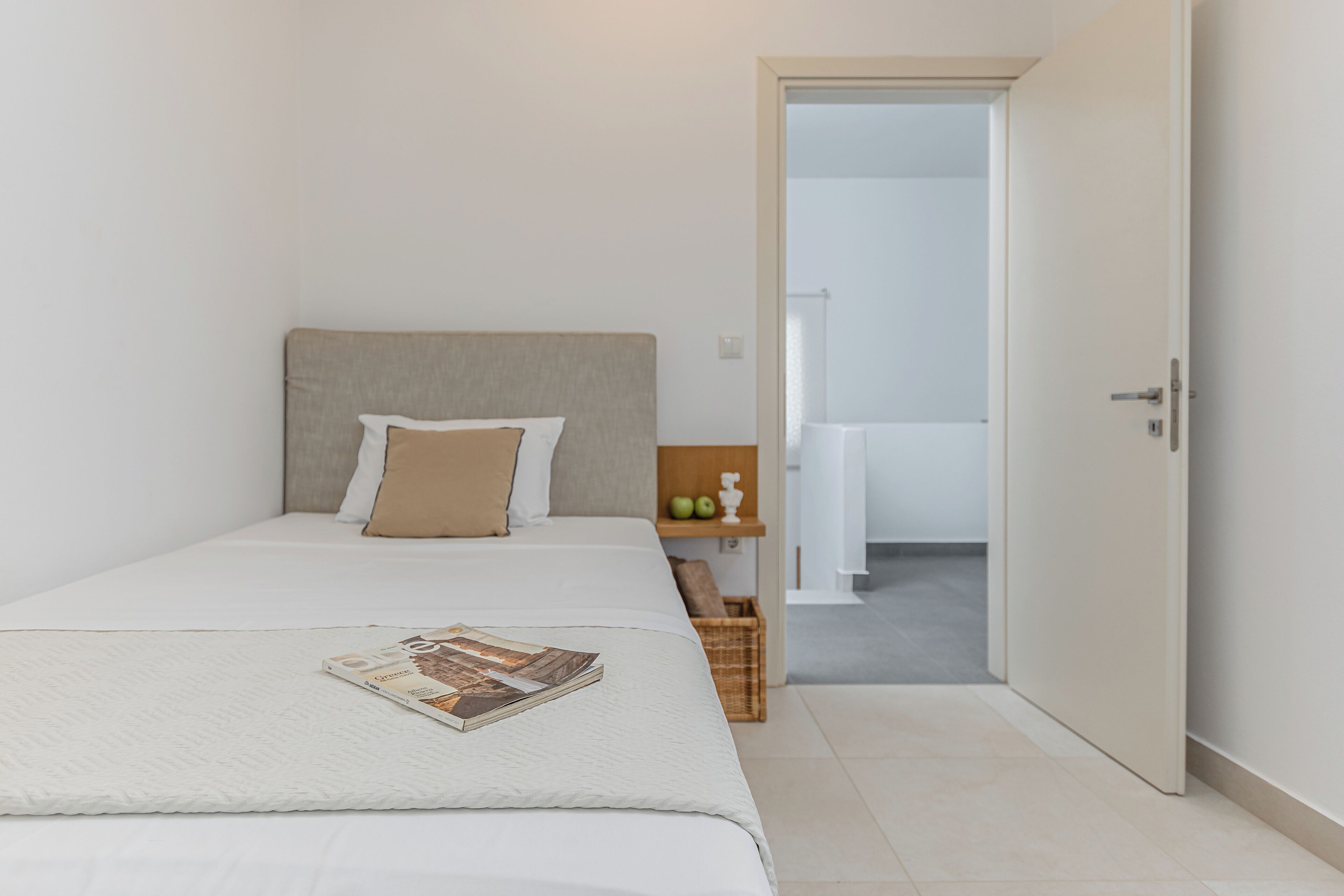 Un dormitorio con una cama, una mesita de noche y una puerta que da al baño.