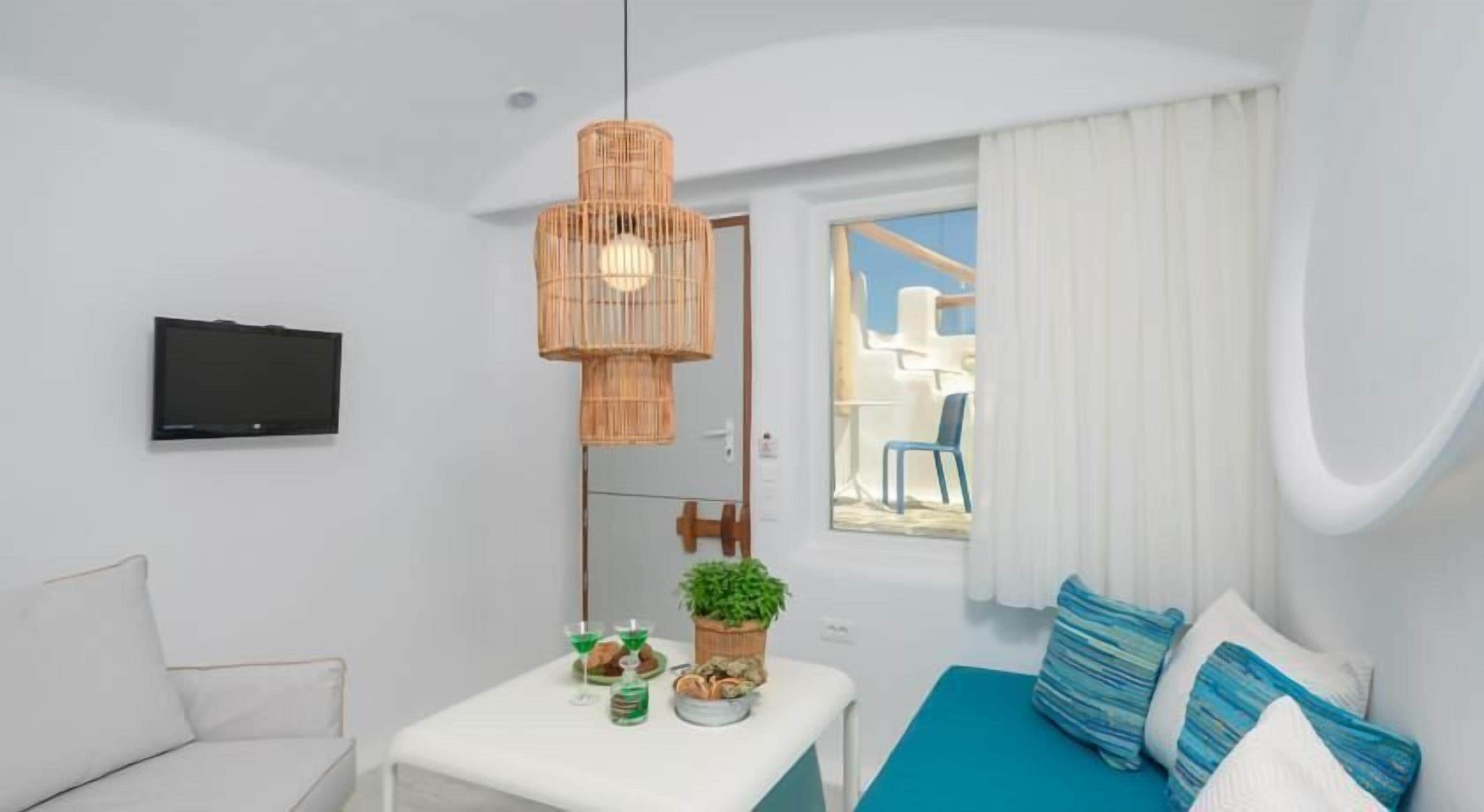 A compact room with a bed, a small table with a plant, a TV, and a window with curtains.