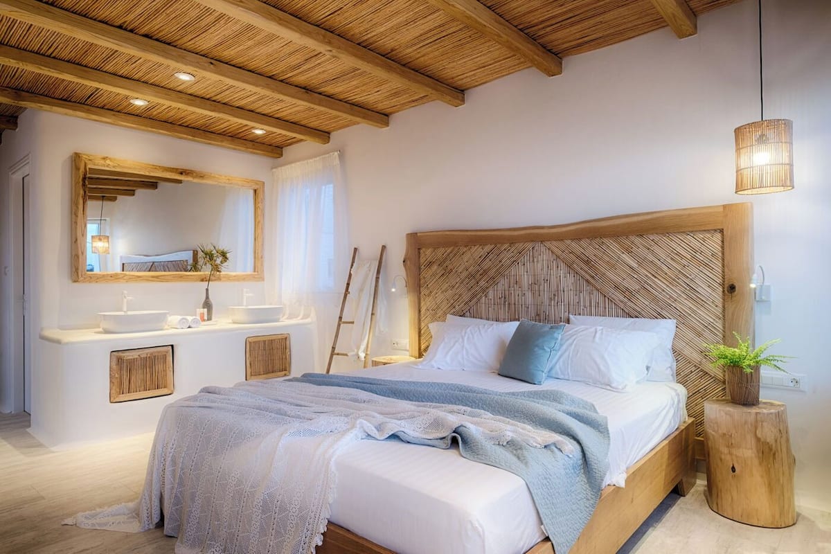 Un dormitorio con una cama grande, cabecero de madera, mesitas de noche y un espejo.