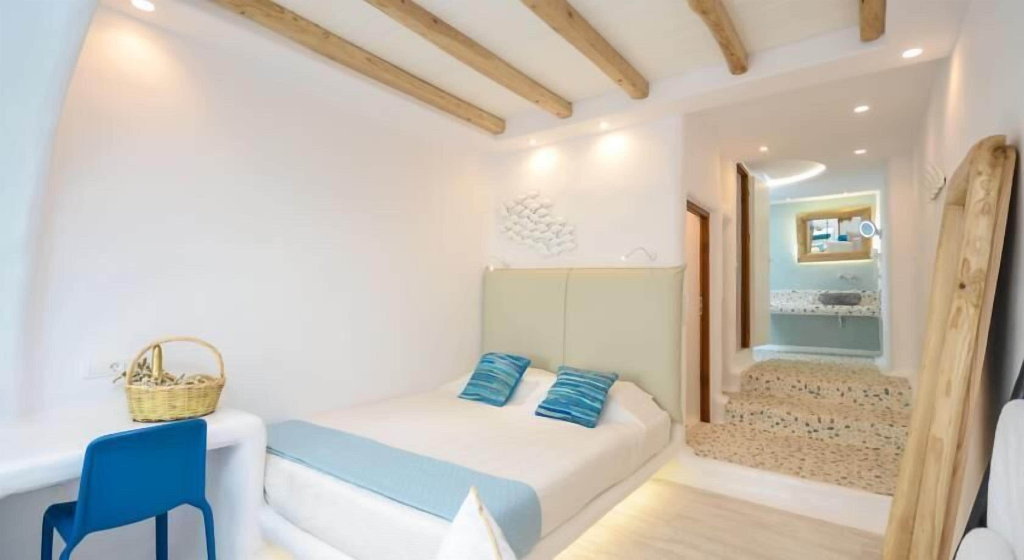 Un dormitorio con cama, una silla, una mesita y una cesta.