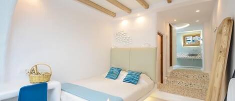 Un dormitorio con cama, una silla, una mesita y una cesta.