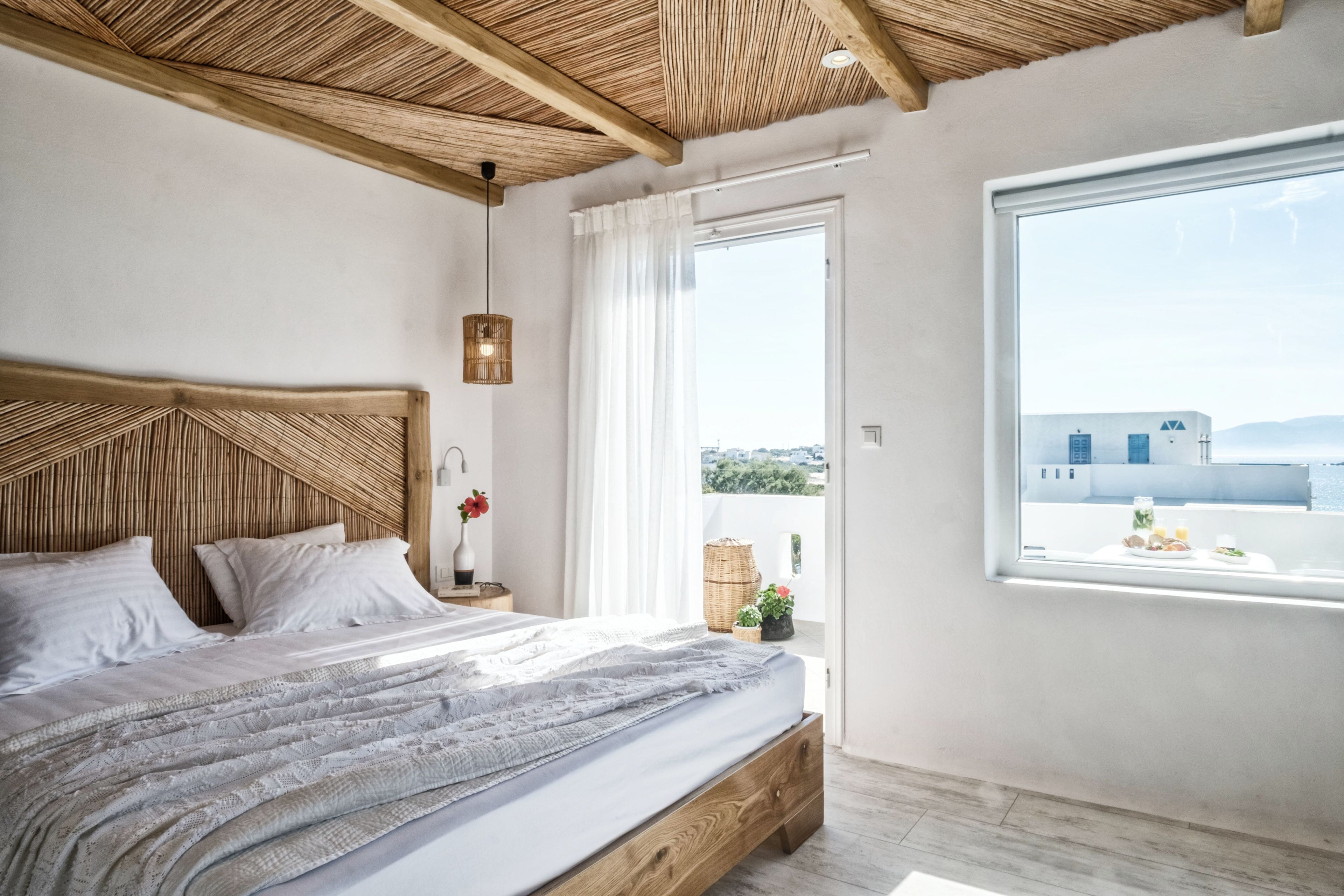 Ein Schlafzimmer mit einem Holzkopfende, einem großen Fenster mit Aussicht und einem Nachttisch mit Lampe.