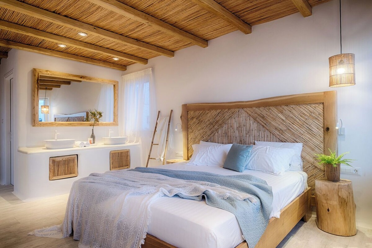 A bedroom with a large bed, wooden headboard, bedside tables, and a mirror.