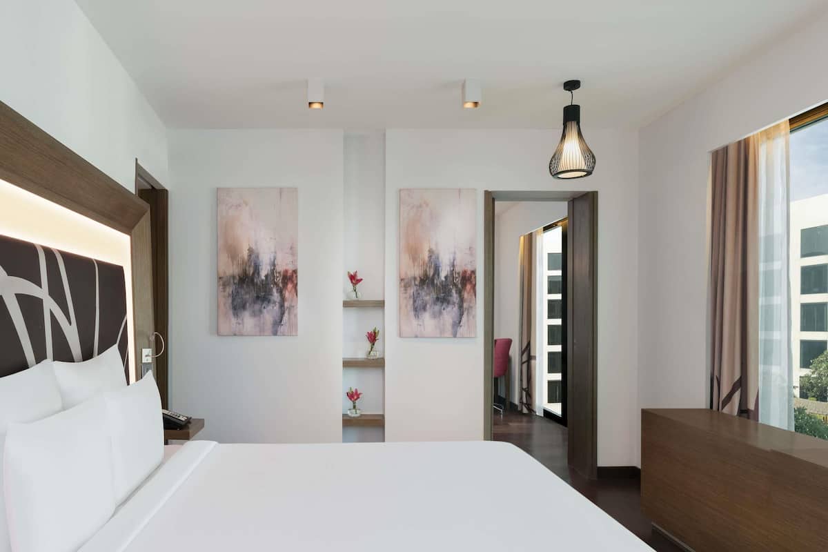 Een moderne hotelkamer met een groot bed, abstracte wanddecoratie, een bureau en uitzicht op de omgeving.