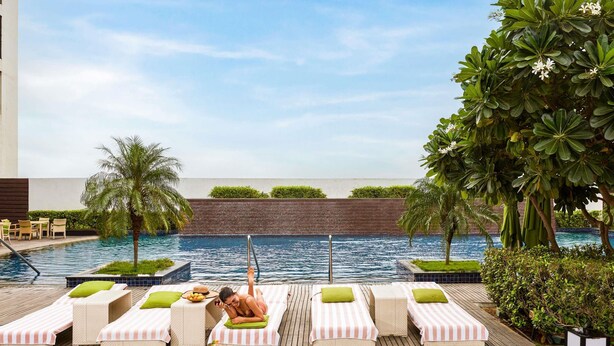 A poolside area with lounge chairs, a palm tree, and a view of the pool.
