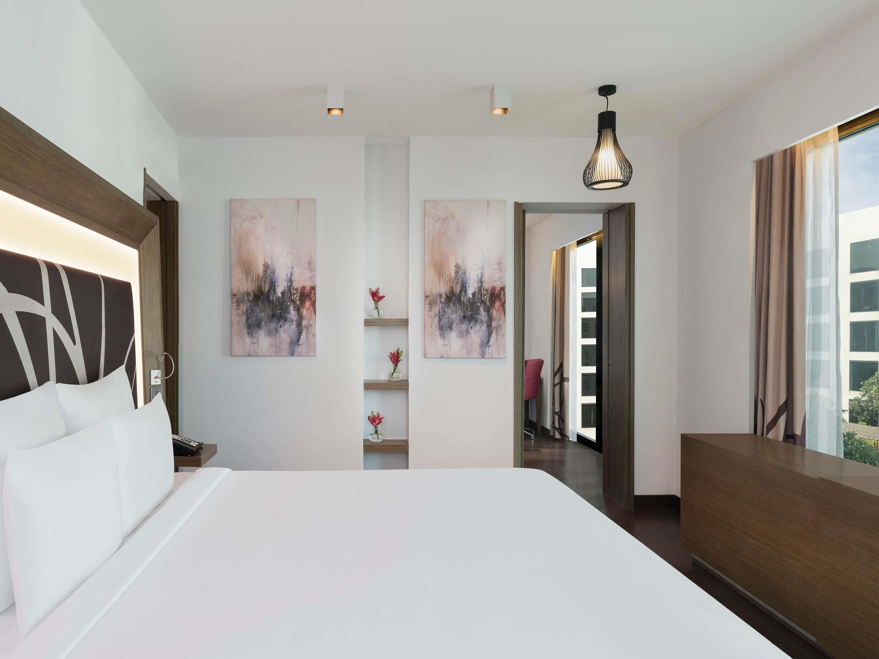 Een moderne hotelkamer met een groot bed, kunst aan de muur, een bureau en uitzicht naar buiten.