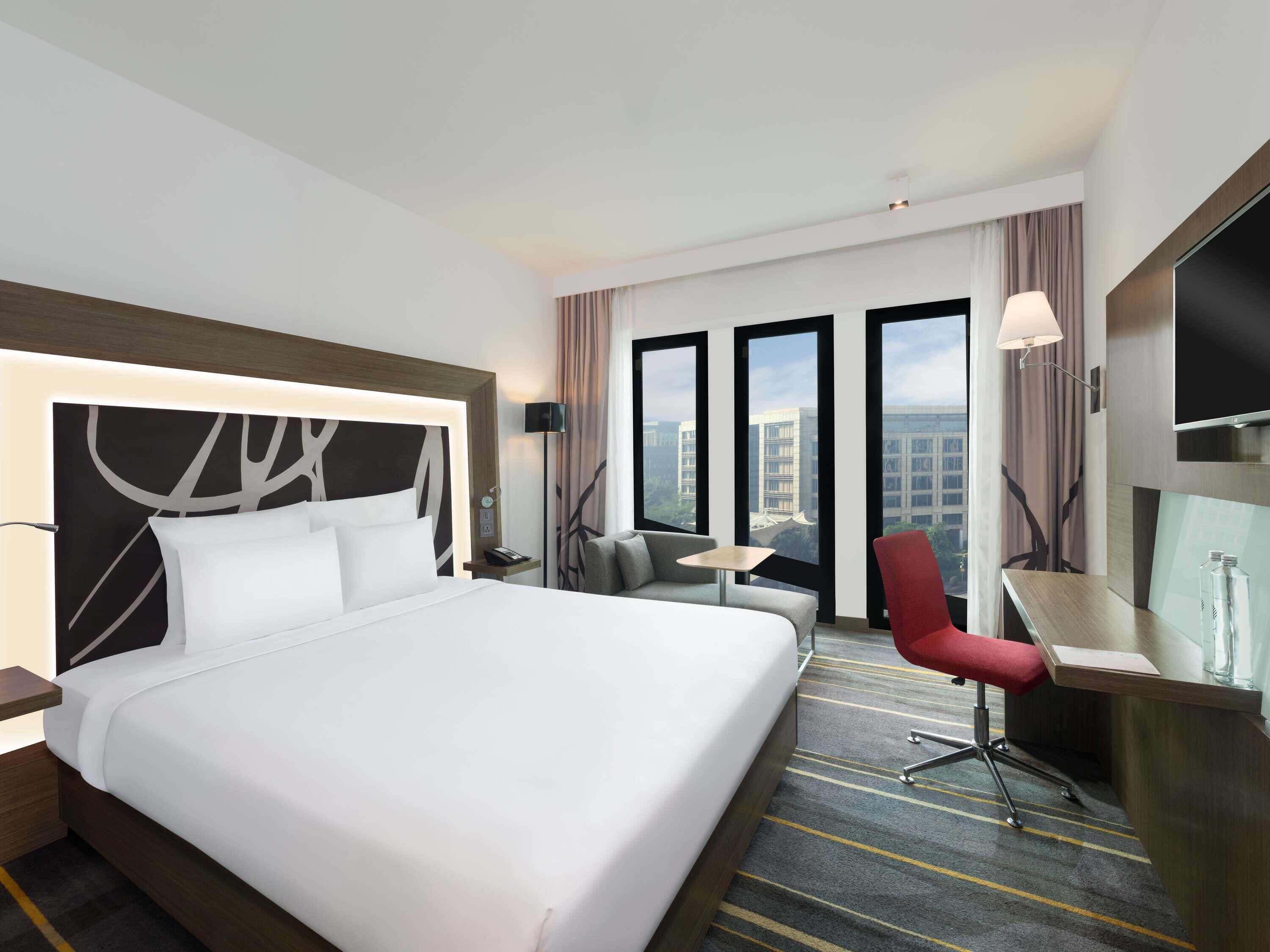 Een hotelkamer met een groot bed, een bureau, een stoel en een televisie.