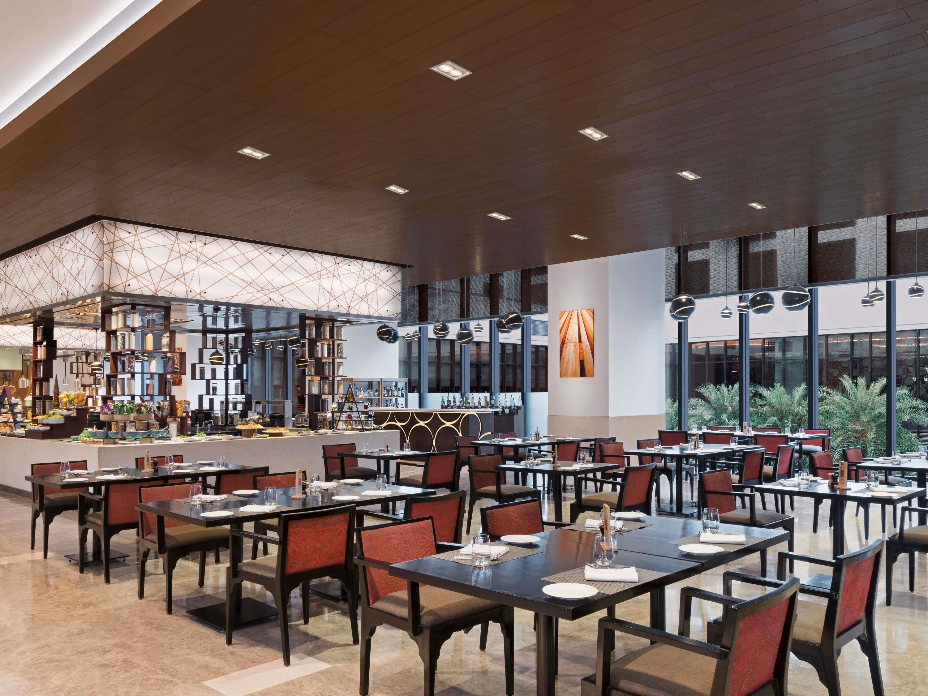 Un restaurant spacieux, doté de nombreuses tables et chaises, d’un bar et de grandes fenêtres offrant une vue panoramique.