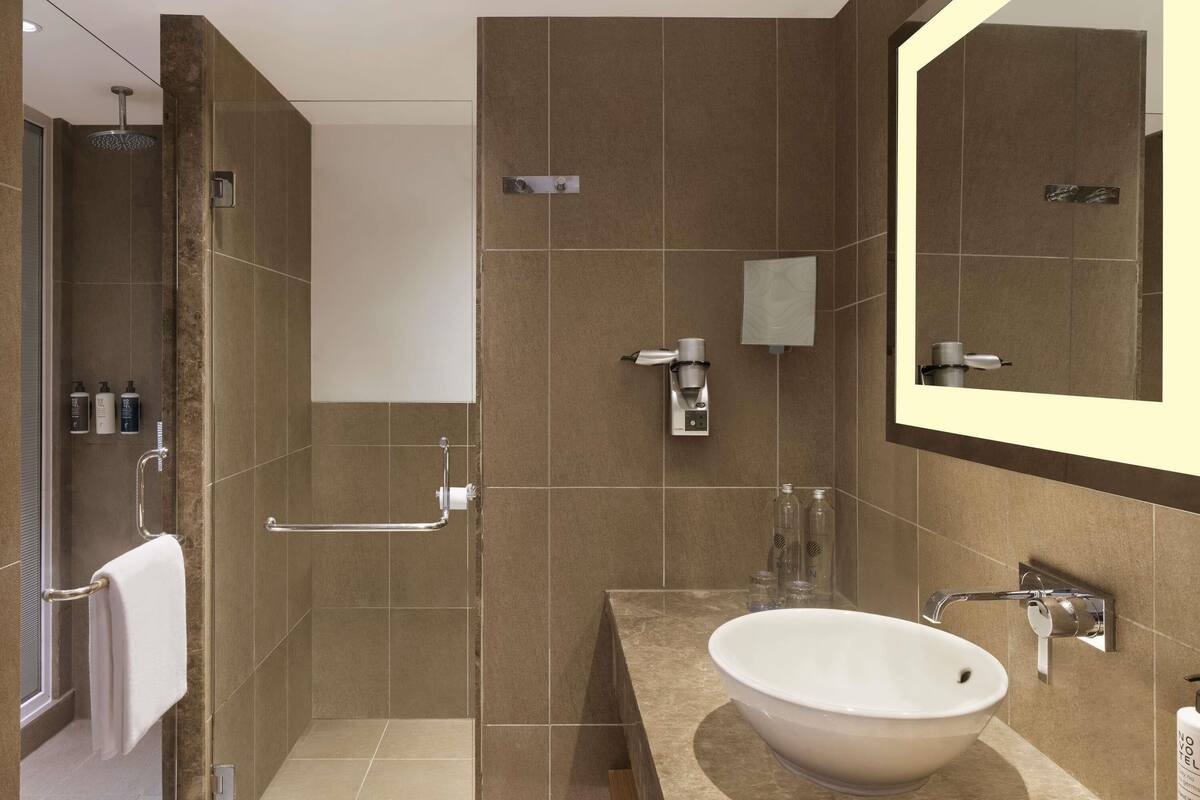 Een moderne badkamer met een grote spiegel, een wastafel en een douchehoek.