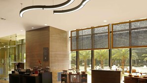 A modern lobby with wooden flooring, a reception desk, and large windows offering a view of the outdoors.