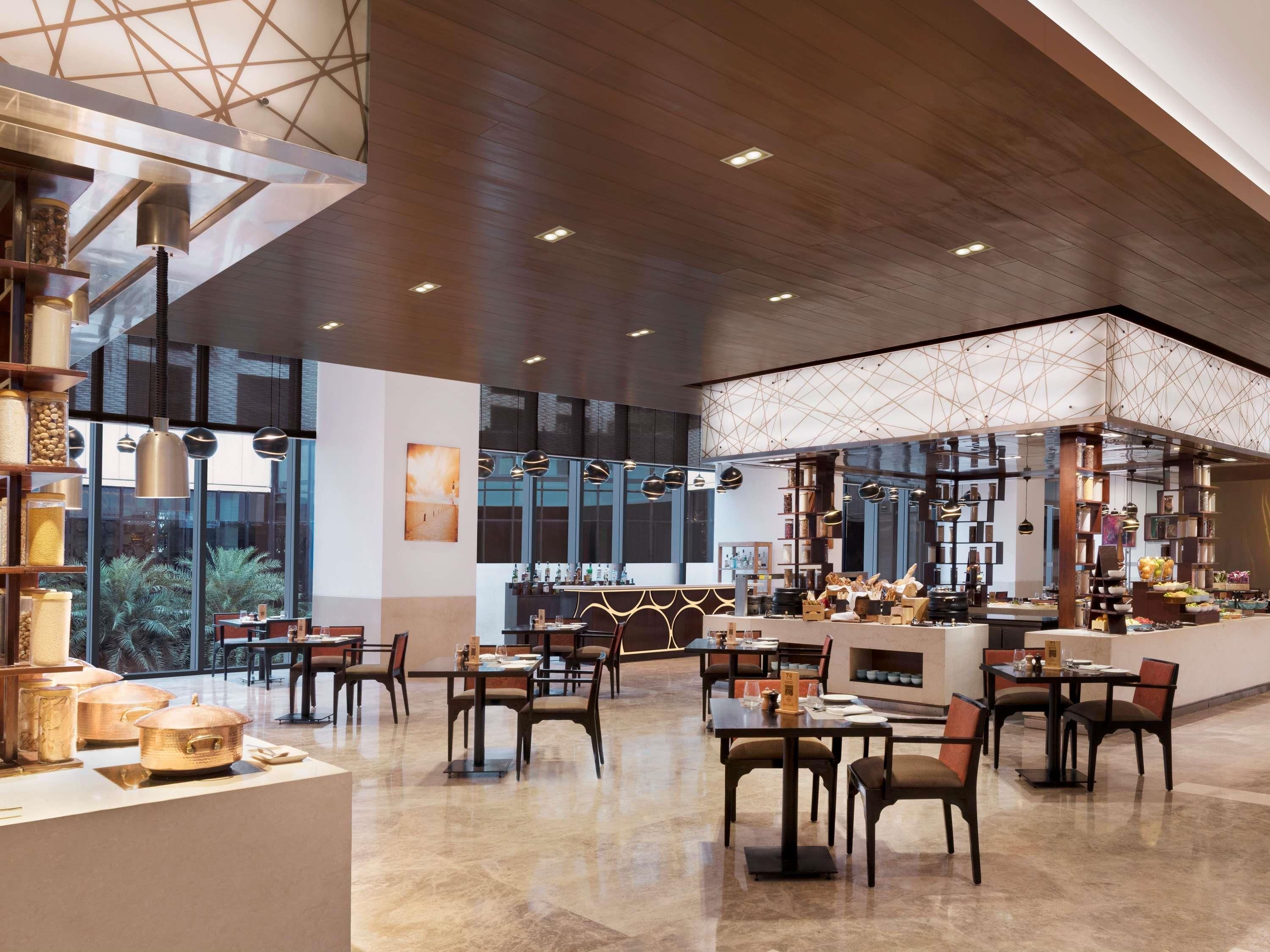 A spacious restaurant with high ceilings, large windows, and a variety of seating arrangements.