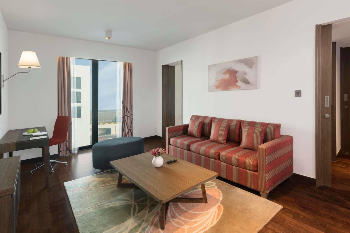 Een moderne hotelkamer met een bank, een salontafel, een bureau en een stoel.