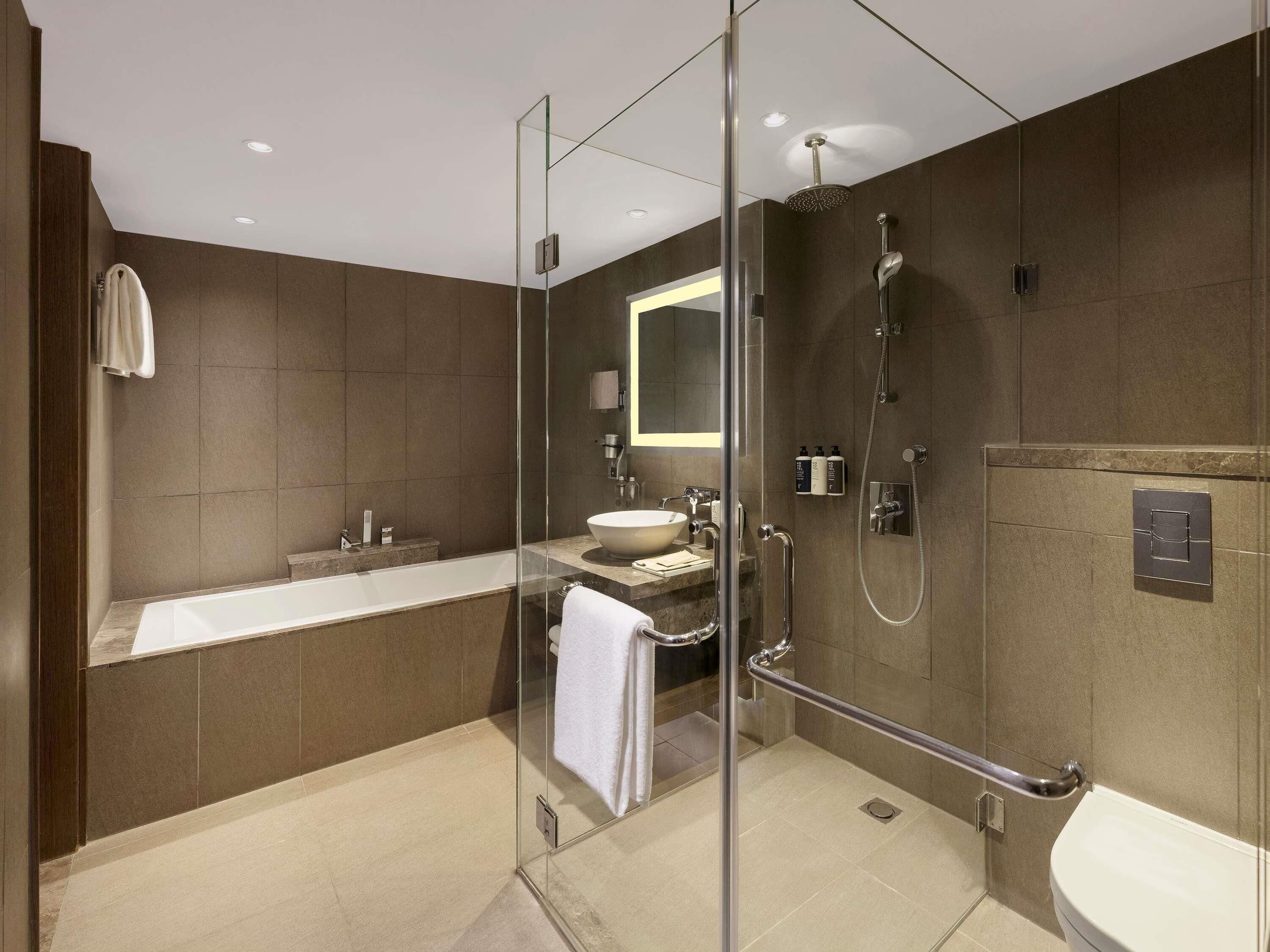 A modern bathroom with a glass-enclosed shower, a standalone bathtub, and a toilet.