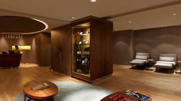 Un vestíbulo de hotel con una recepción, una zona de estar con sillones, una mesa de centro con revistas y una pieza decorativa en la pared.