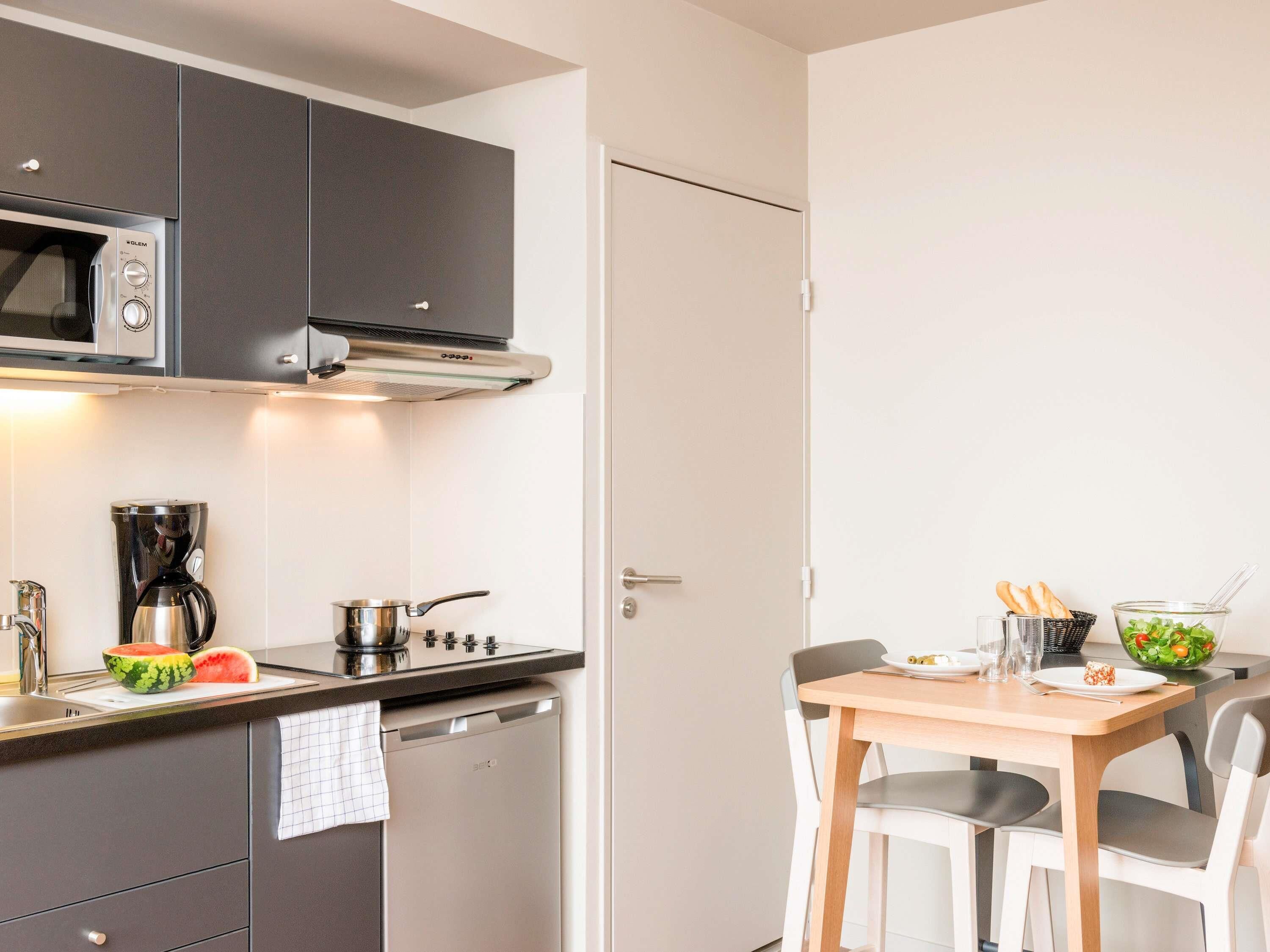 Una cocina moderna con armarios oscuros, microondas, cafetera, estufa y lavavajillas.