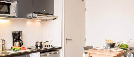 Una cocina moderna con armarios oscuros, microondas, cafetera, estufa y lavavajillas.