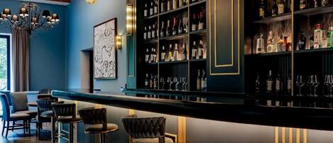A bar area with a dark wood bar counter, multiple shelves of liquor bottles, and bar stools.