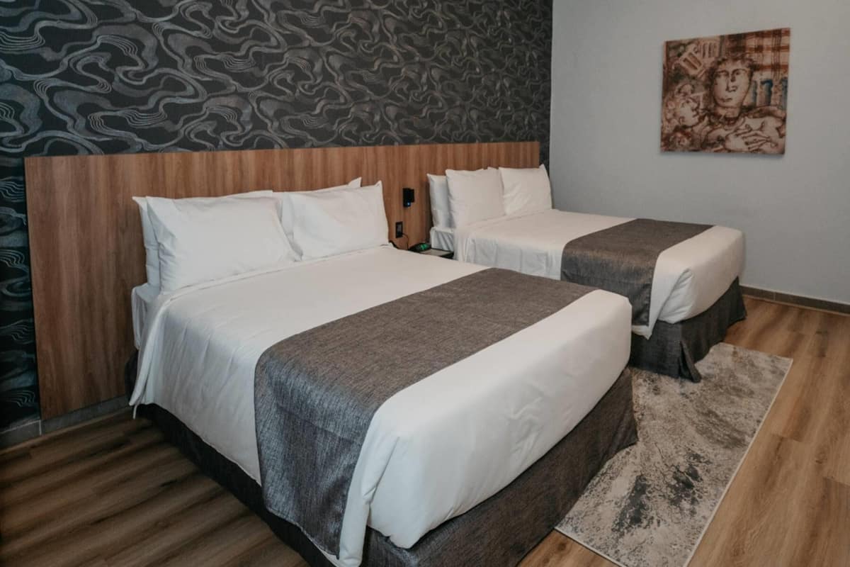 Ein Doppelzimmer mit zwei Betten, einem Holz-Kopfteil, einer Wand mit Muster und einem Gemälde.
