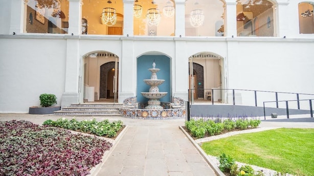 A courtyard with a central fountain, arched windows, and a pathway leading to the entrance. - Hotel Ex hacienda Chautla Puebla, Trademark by Wyndham (San Salvador el Verde)