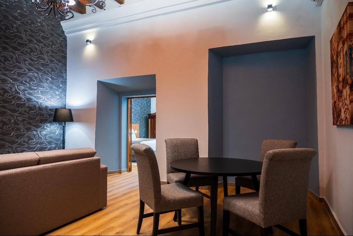 Una sala de estar moderna con una mesa redonda y cuatro sillas, un sofá y un muro con diseño.
