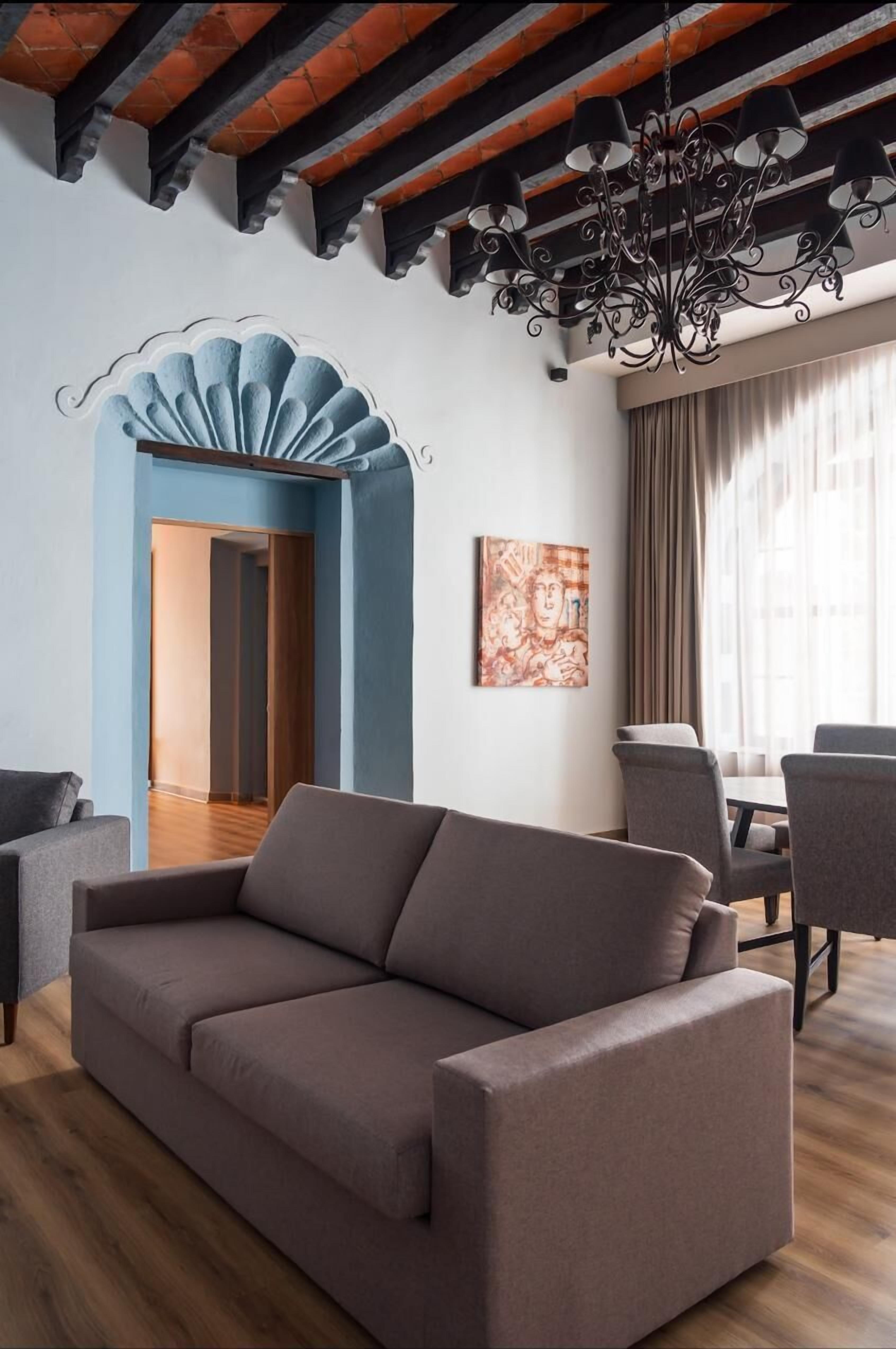 Ein modernes Wohnzimmer mit braunem Sofa, einer Kristallleuchtre und einer blauen Akzentwand.