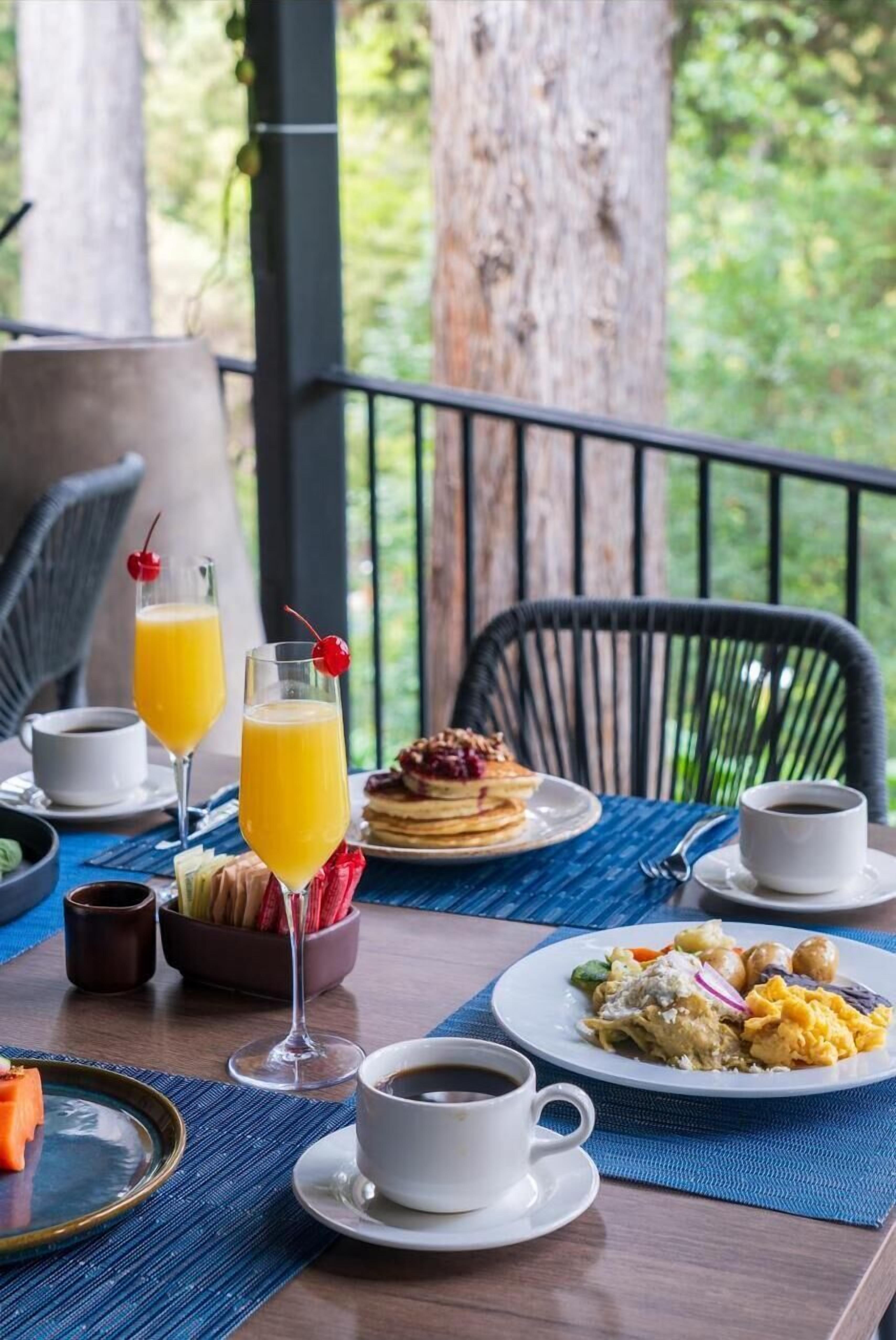 A breakfast setting with a table, plates of food, glasses of orange juice, and a cup of coffee.