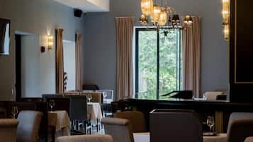 Ein Restaurant mit gedeckten Tischen, einem Kronleuchter und Blick ins Freie.
