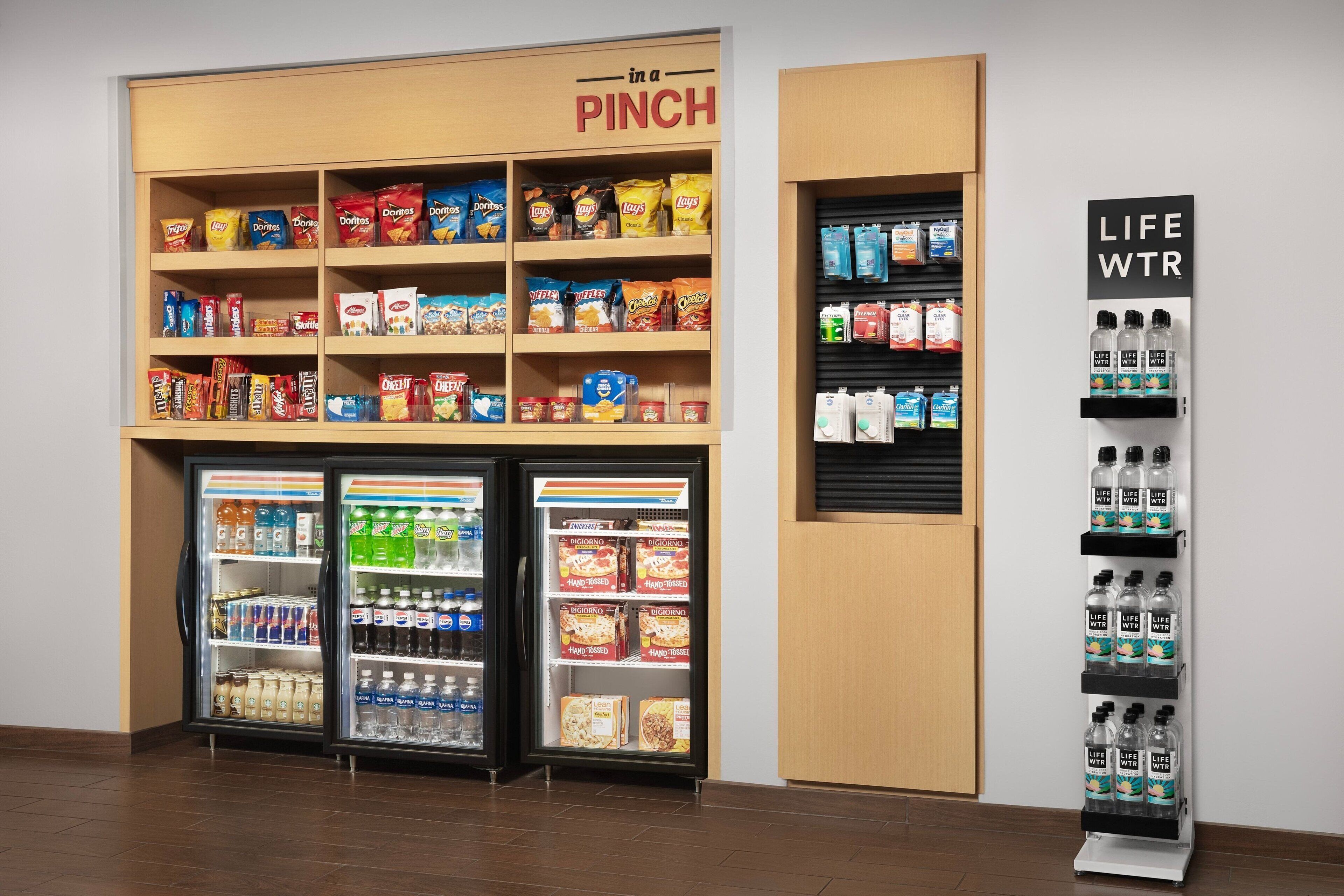 A snack and beverage section in a store with shelves stocked with chips, snacks, and bottled drinks.