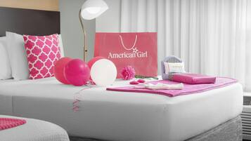 A hotel room with a bed, pillows, a lamp, a shopping bag, balloons, and a gift box.