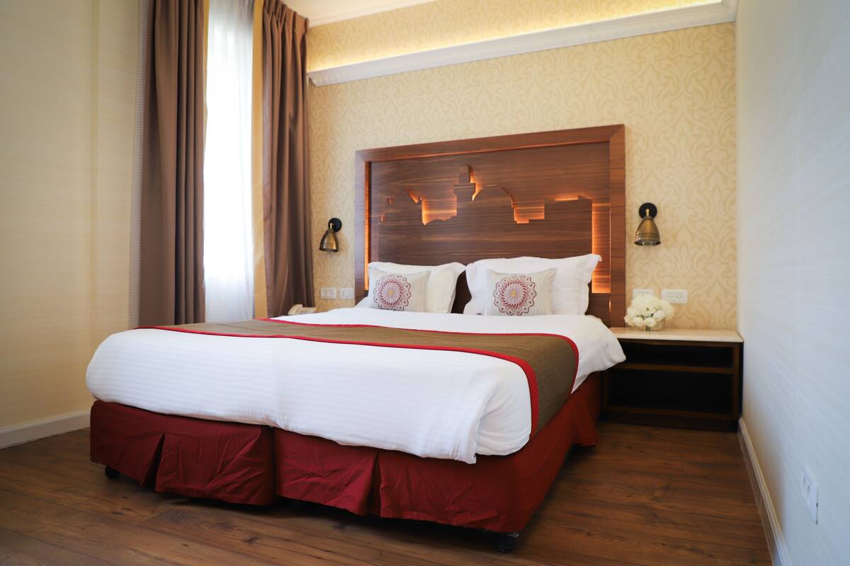 Une chambre d’hôtel avec un grand lit, une tête de lit en bois et deux tables de chevet avec des lampes.
