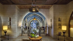 A grand hallway with a central table, chandeliers, and a decorative ceiling. - YMCA Three Arches Hotel (Jerusalem)