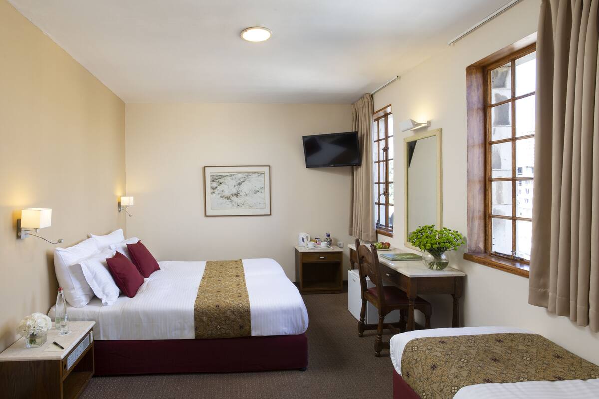 Une chambre d’hôtel avec un lit, un bureau, une chaise, une télévision et une fenêtre.