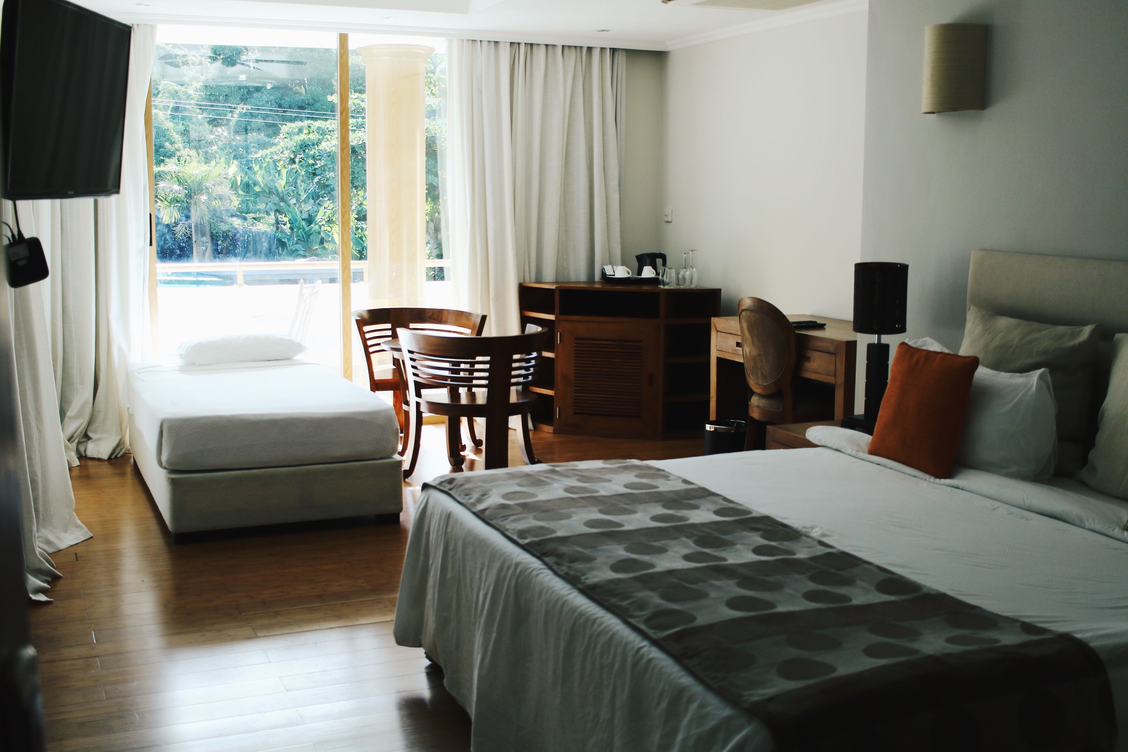 Ein Hotelzimmer mit Bett, Schreibtisch, Stuhl und einem fenster mit Vorhängen.