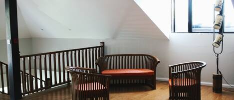 A spacious loft with a high ceiling, a wooden staircase, and a large window providing natural light.