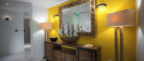 A hallway with a wooden console table, a ship model, and a mirror with a rope light.