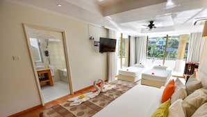Habitación de hotel con una cama grande, un televisor montado en la pared, un balcón con vistas a zonas verdes y un área de ducha.