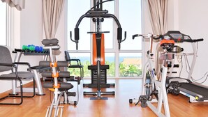Une salle de sport à domicile équipée d’un tapis de course, d’un banc de musculation et d’autres appareils d’exercice.