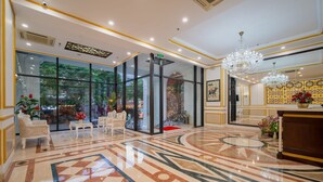 Un hall d’hôtel avec un sol en marbre, un comptoir d’accueil et un lustre.
