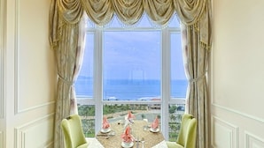Un coin repas avec une table dressée pour deux personnes, offrant une vue panoramique sur l’océan et la silhouette lointaine de la ville.
