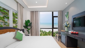 Une chambre d’hôtel moderne avec un grand lit, un bureau et une vue sur la plage.