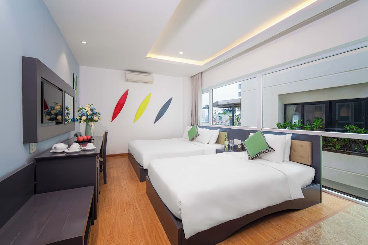 A modern hotel room with two beds, a dining table, and a large window offering a view of the outdoors.